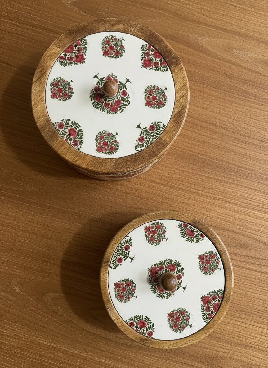 Two wooden containers with floral patterns on wooden lids on a wooden surface
