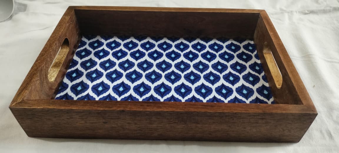 Wooden tray with blue and white patterned fabric inside on a light background