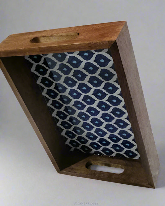 Wooden tray with a blue and white patterned fabric inside on a light gray background